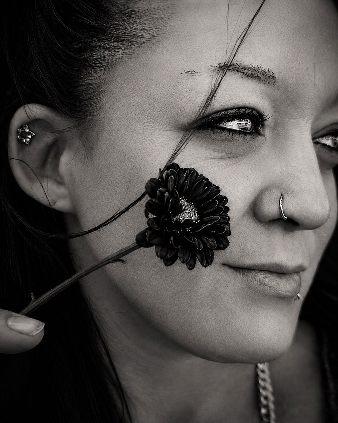 Woman with a flower held against her cheek — B&W portrait by Sidewalk Stories Photography, Kawkawlin Michigan