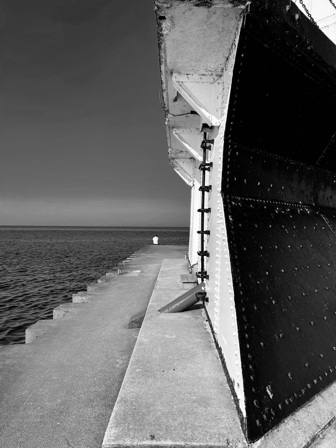 Base of a lighthouse with a solitary figure — weathered stone and fading light, fine art black and white landscape by Craig Moyers, Lake Michigan photographer