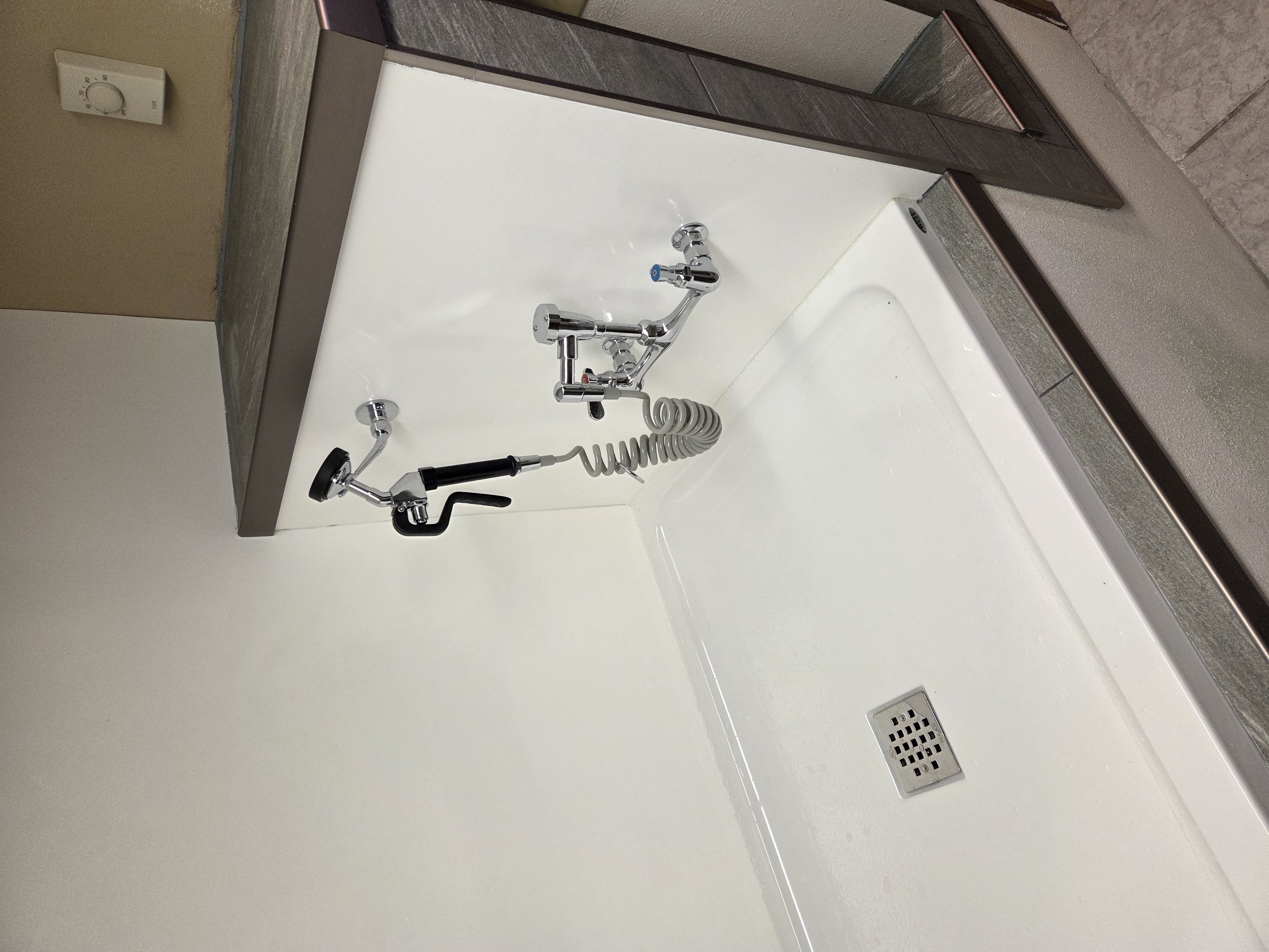 Completed sprayer faucet with coiled hose and floor drain