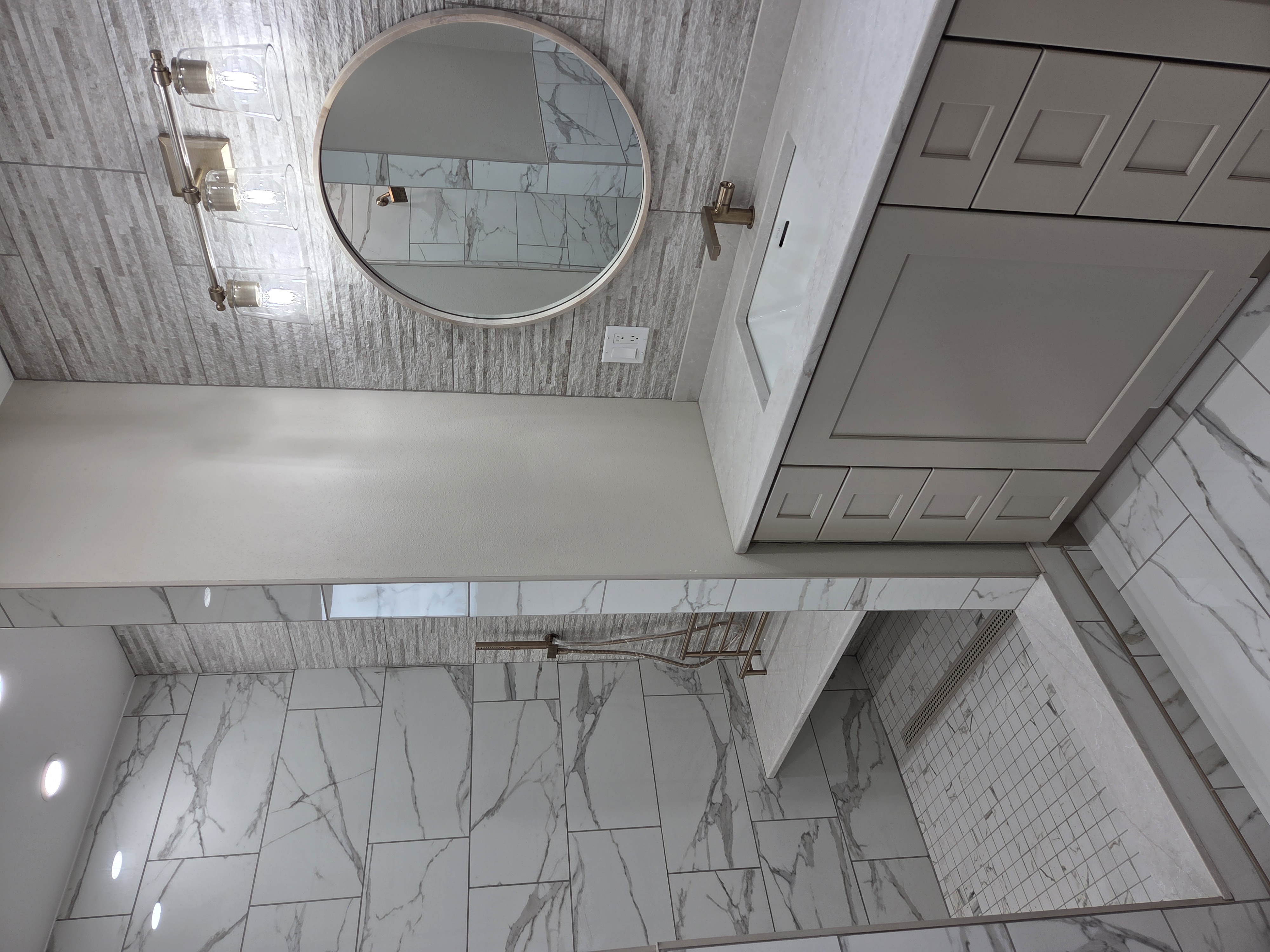 Custom walk-in shower with marble tile, built-in bench, and brushed nickel fixtures by NM Bath Upgrades