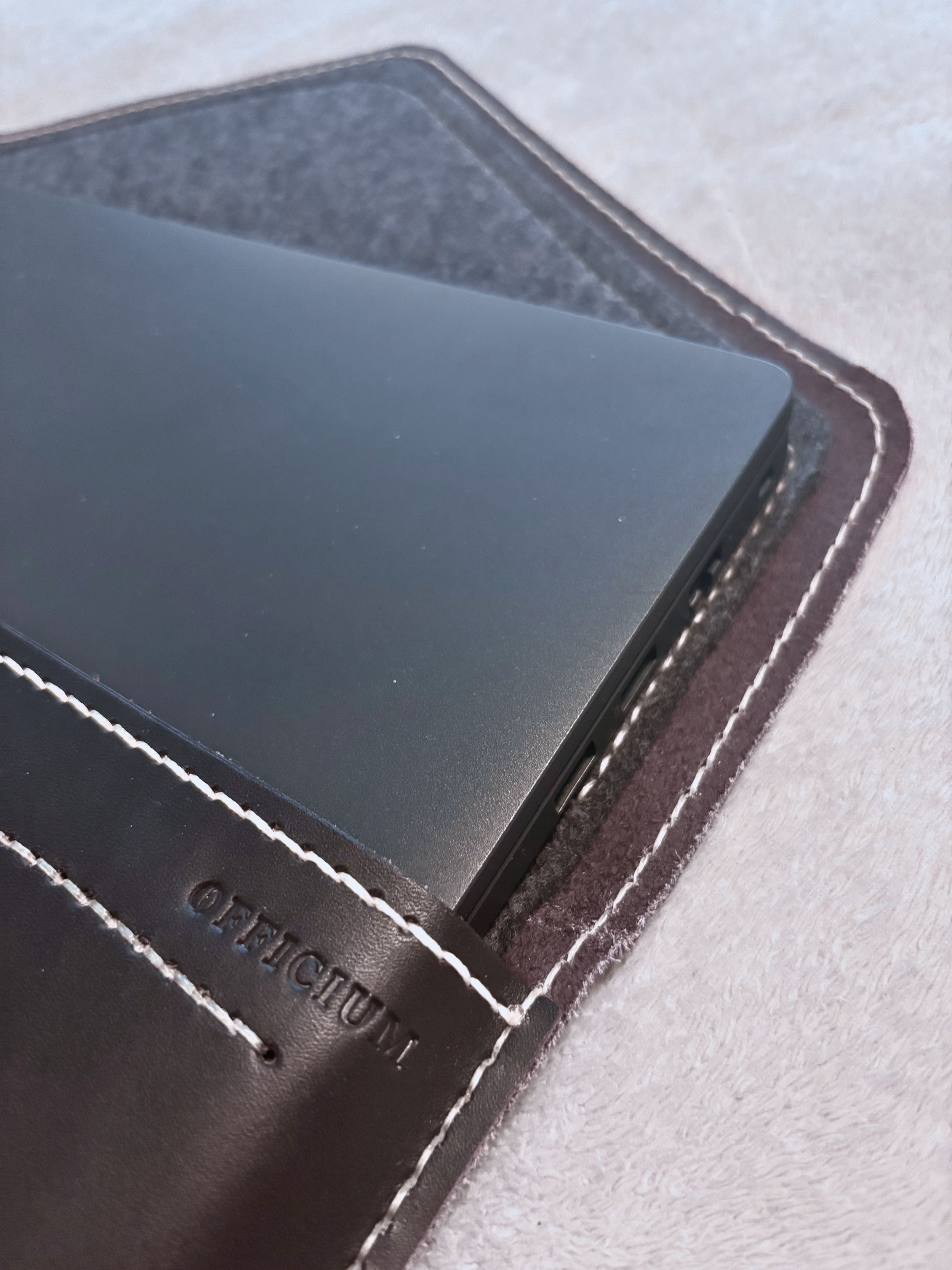 OFFICIUM stamp close-up — hand-burnished edges and saddle-stitching detail