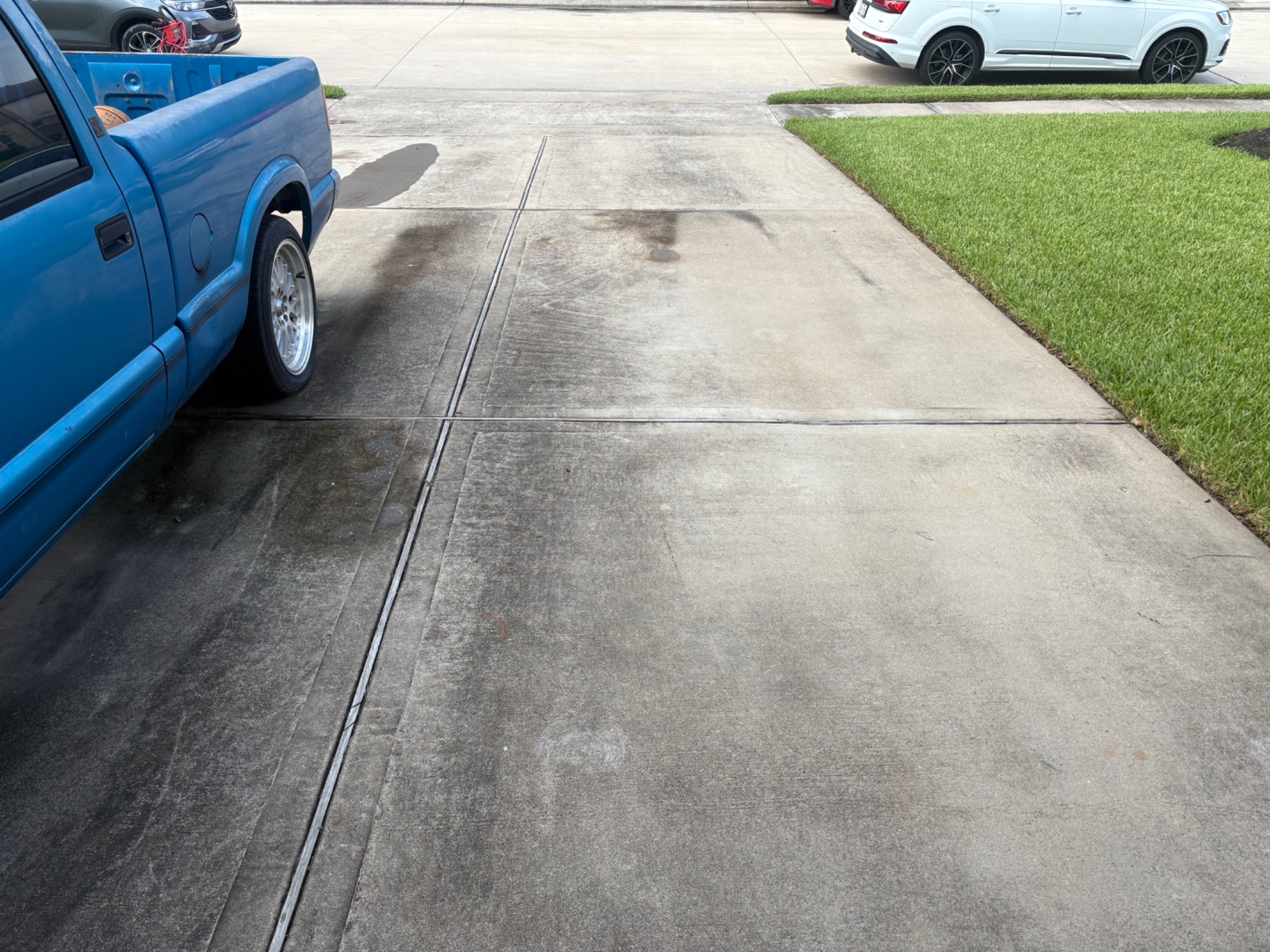 Driveway before pressure washing — stained, weathered concrete with blue truck