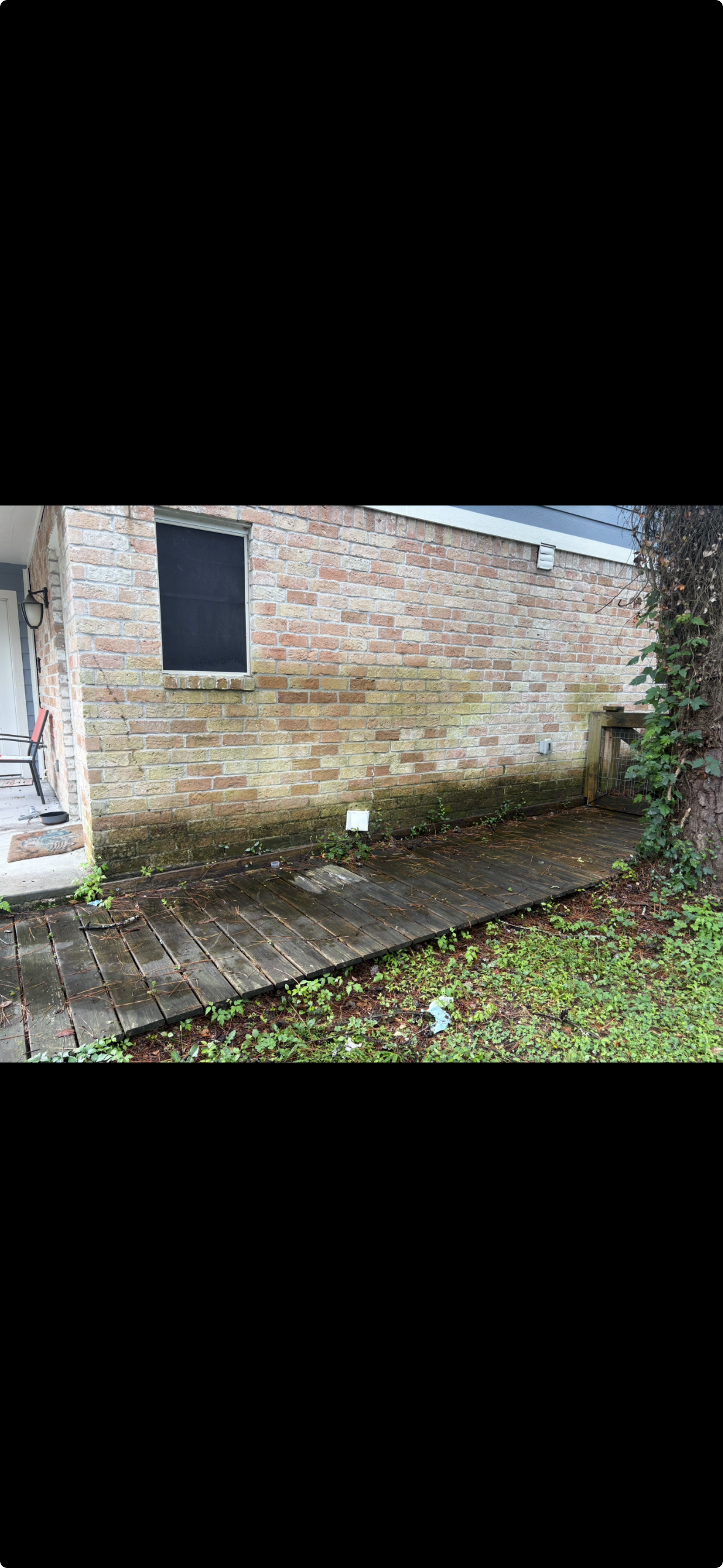 Before pressure washing — dirty brick wall with algae and weathered deck