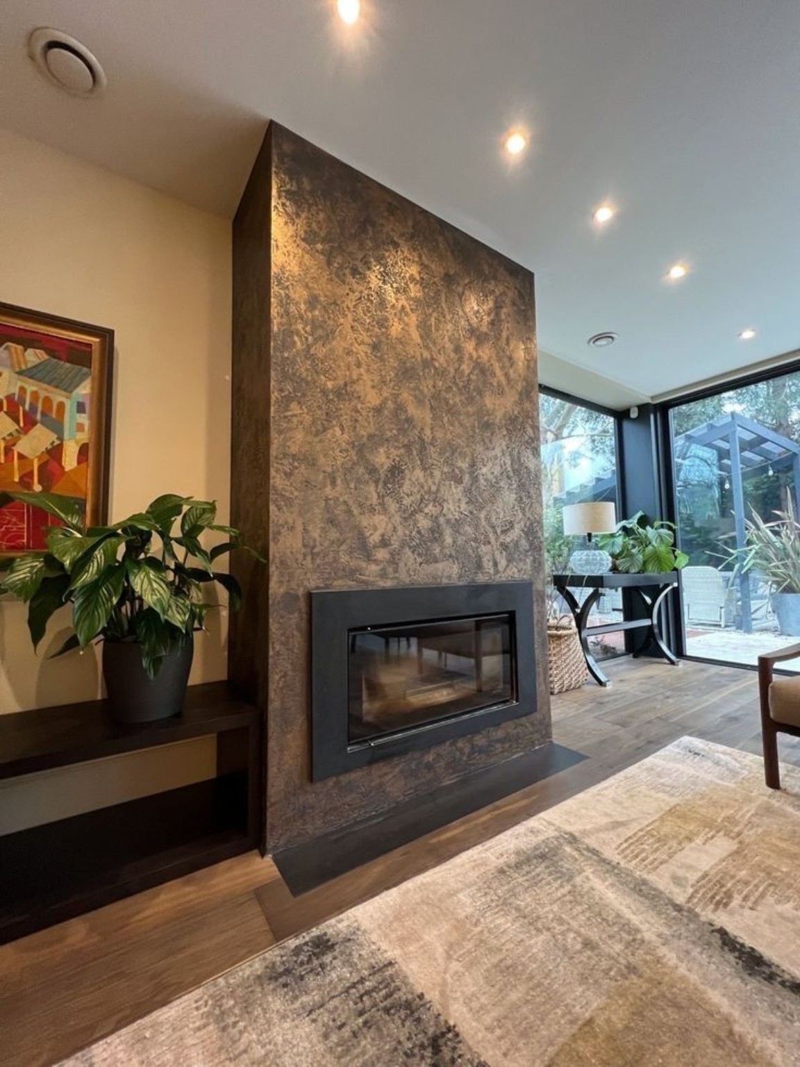 Dark bronze Venetian plaster fireplace — modern linear fireplace with recessed downlighting