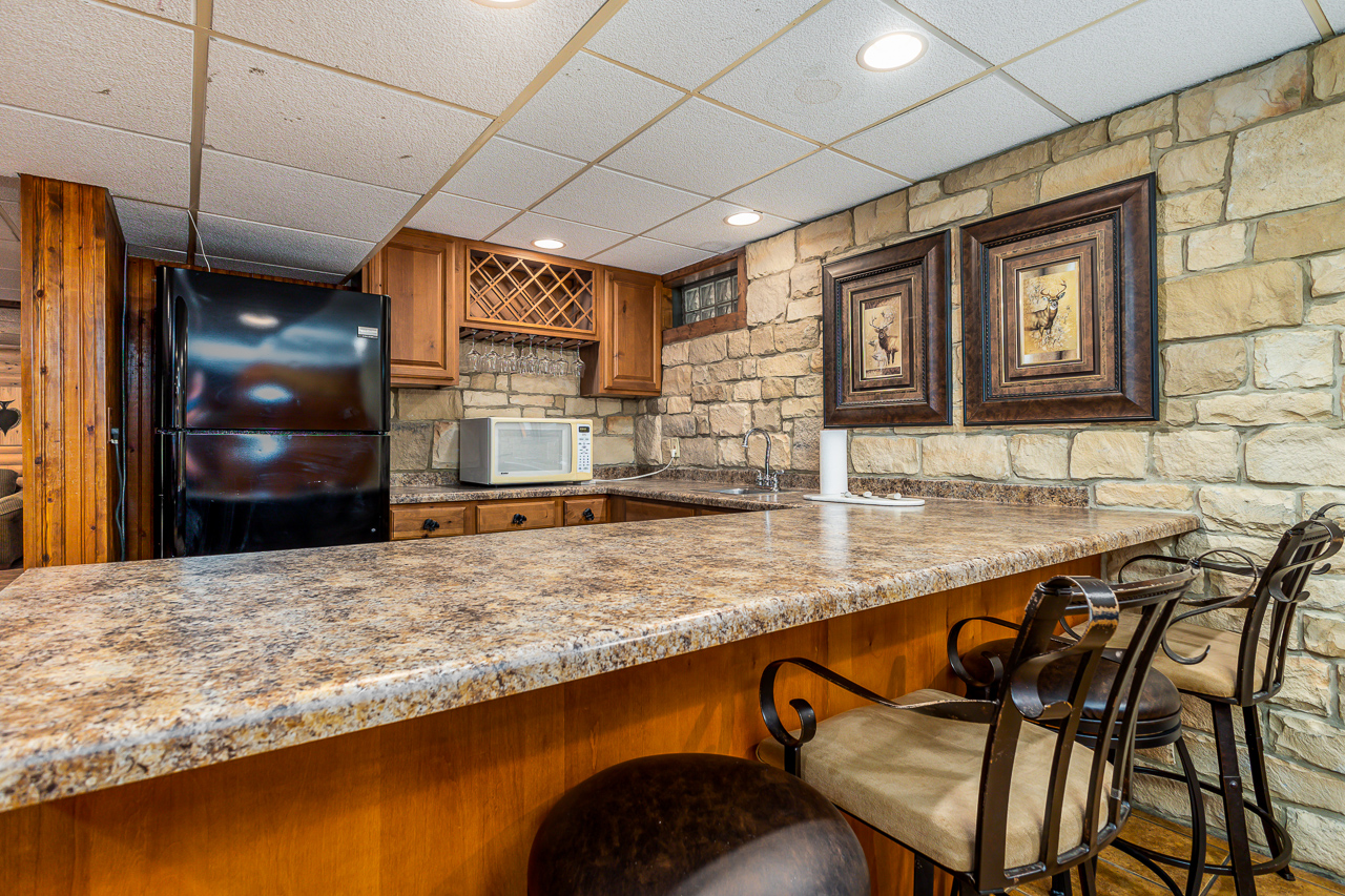 Lower Level Bar with granite counter, wine rack, and bar stools