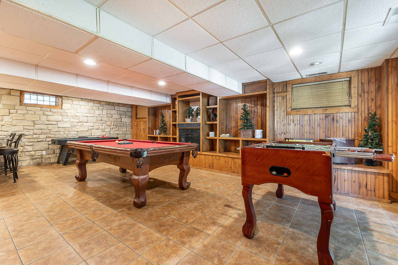 Game Room with pool table, foosball, and stone fireplace