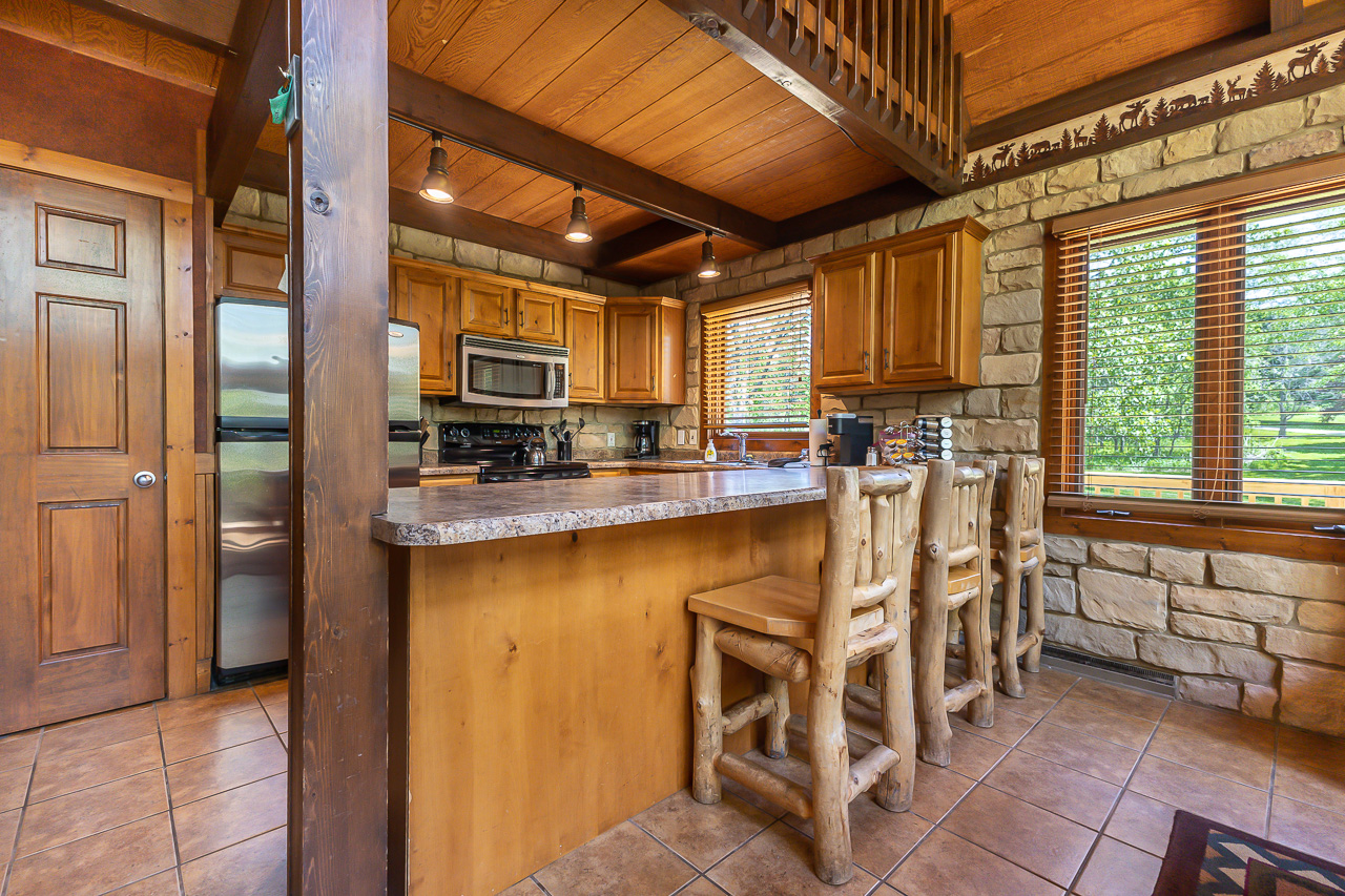 Kitchen with granite counters, log bar stools, and stainless appliances