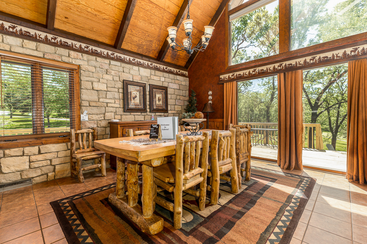 Dining Area with log table, stone wall, and vaulted wood ceiling
