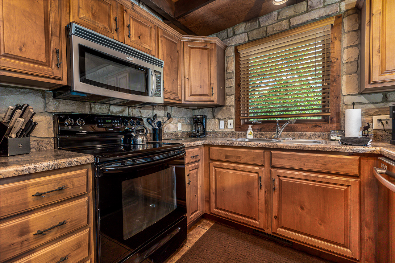 Kitchen appliances with stone backsplash, wood cabinets, and granite counters
