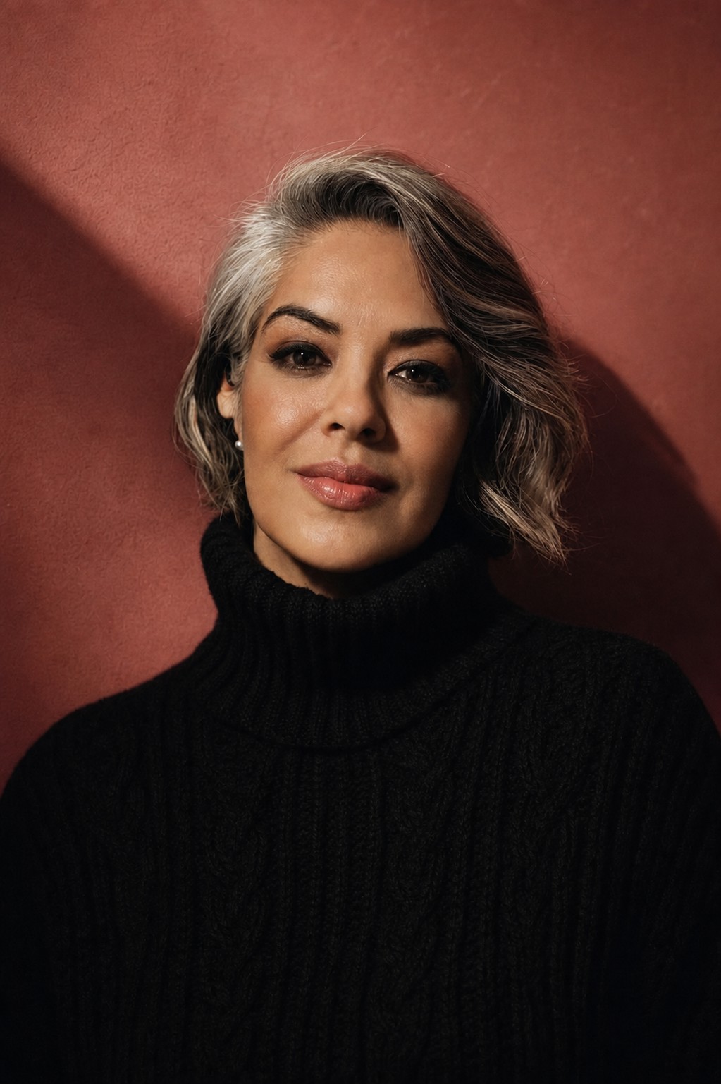 Eterna Femme — portrait of a woman in a dark turtleneck against a warm terracotta backdrop