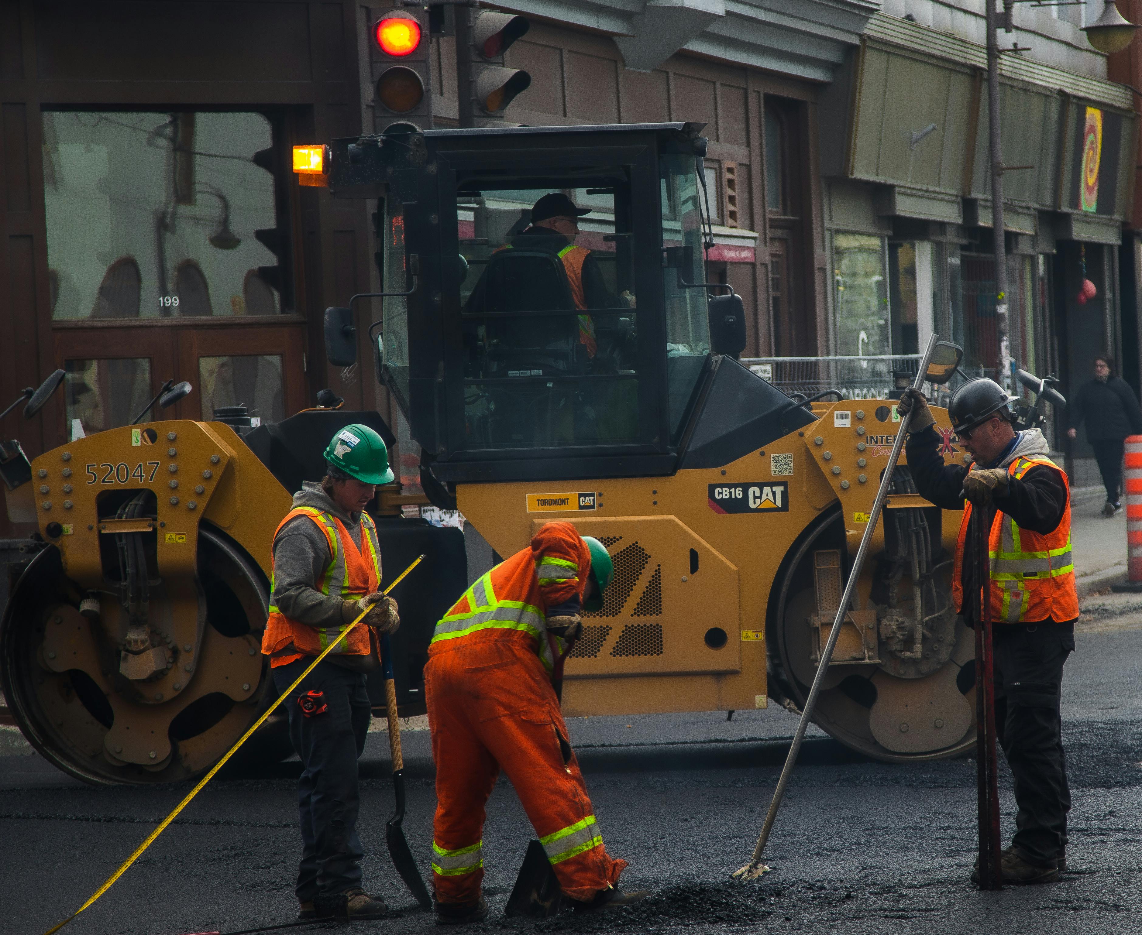 Urban paving operation — CAT CB16 roller with 3 ground workers