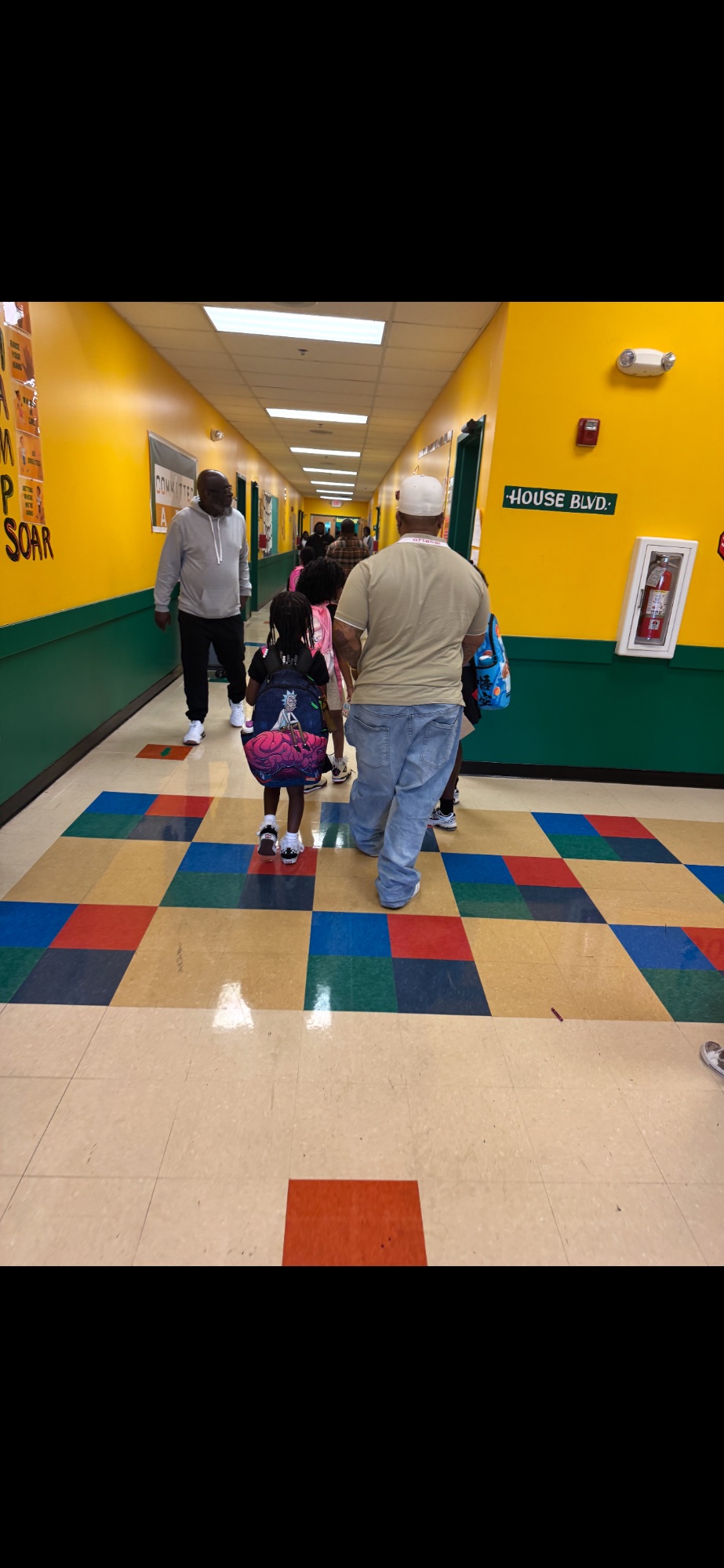 Morris Jackson walking his children down a colorful elementary school hallway