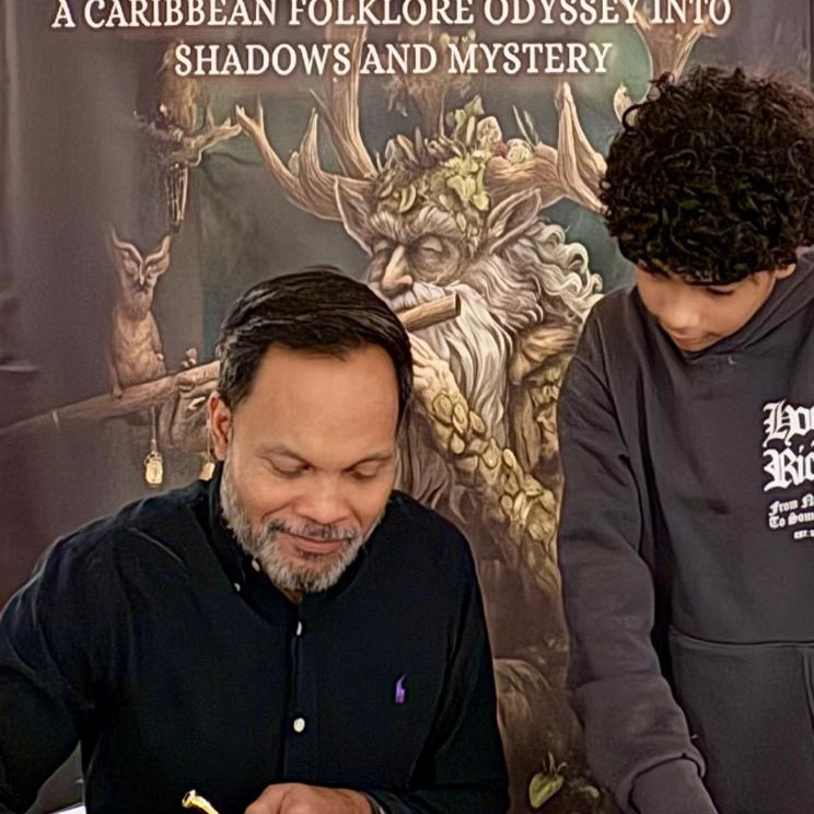 Anthony Mahabir signing copies of Shadows In The Trade Winds at a book event