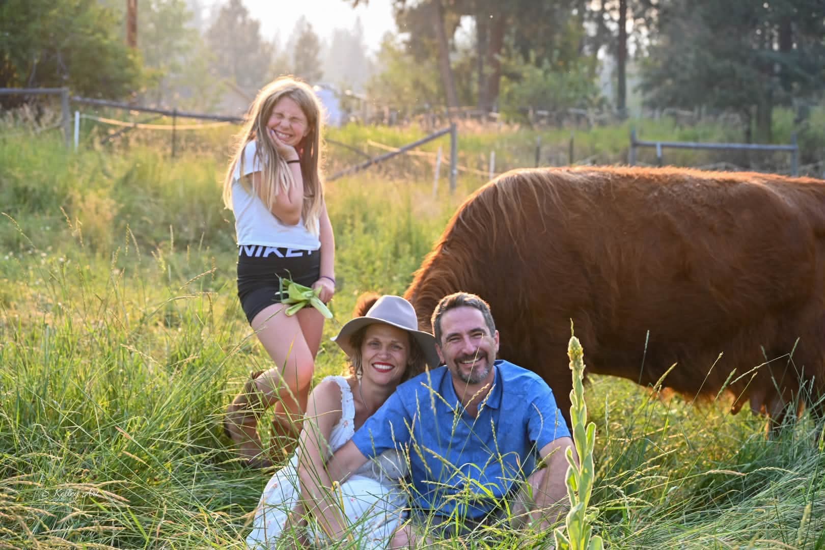 A family of four posed at the Highland-cattle pasture fence under soft overcast light, near Missoula and Clinton, Montana.