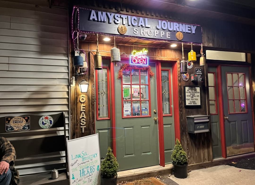 Amystical Journey Shoppe storefront at night — neon Open sign glowing