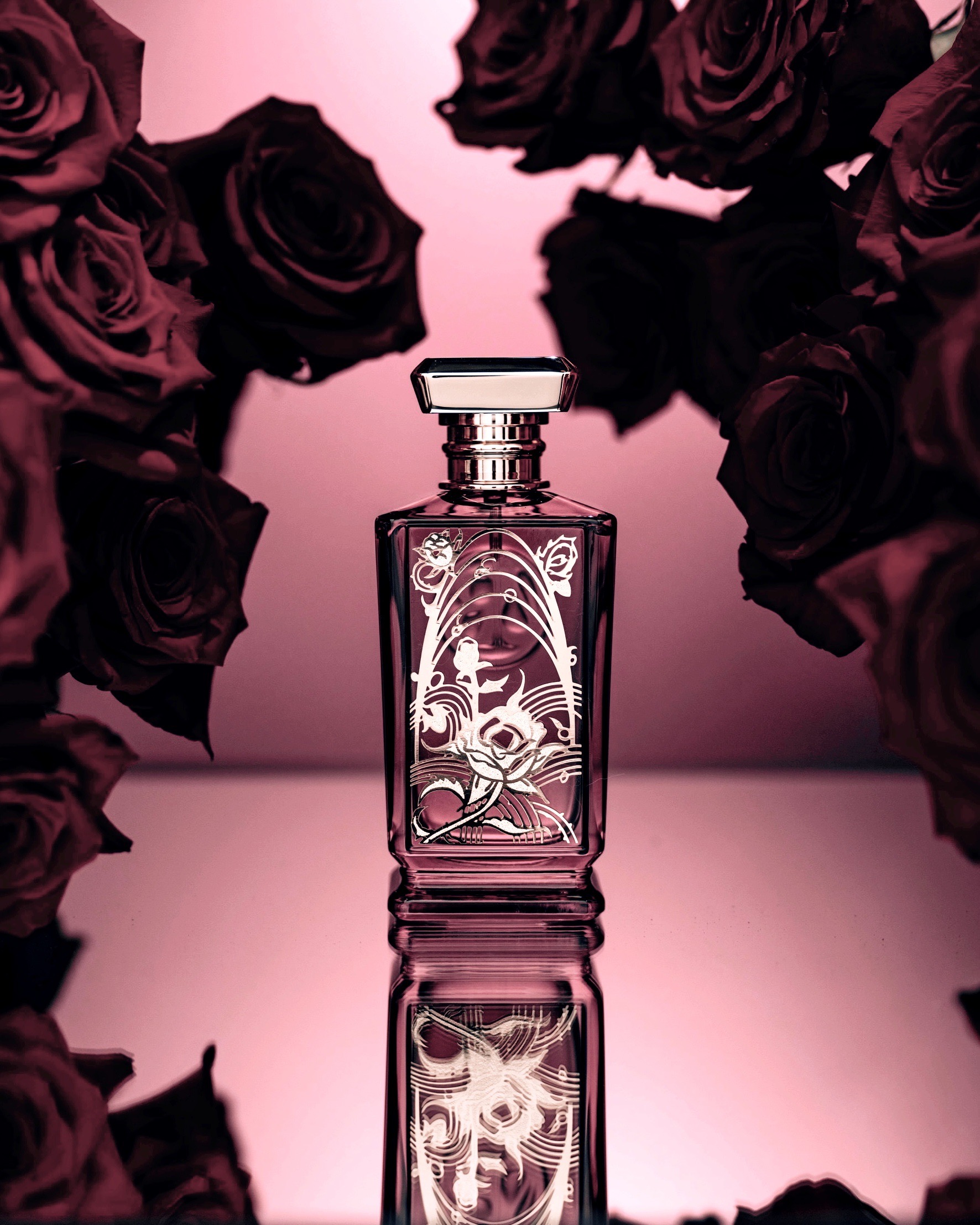 AS IT FLOURISHES — purple perfume bottle framed by dark roses in pink light, reflective surface