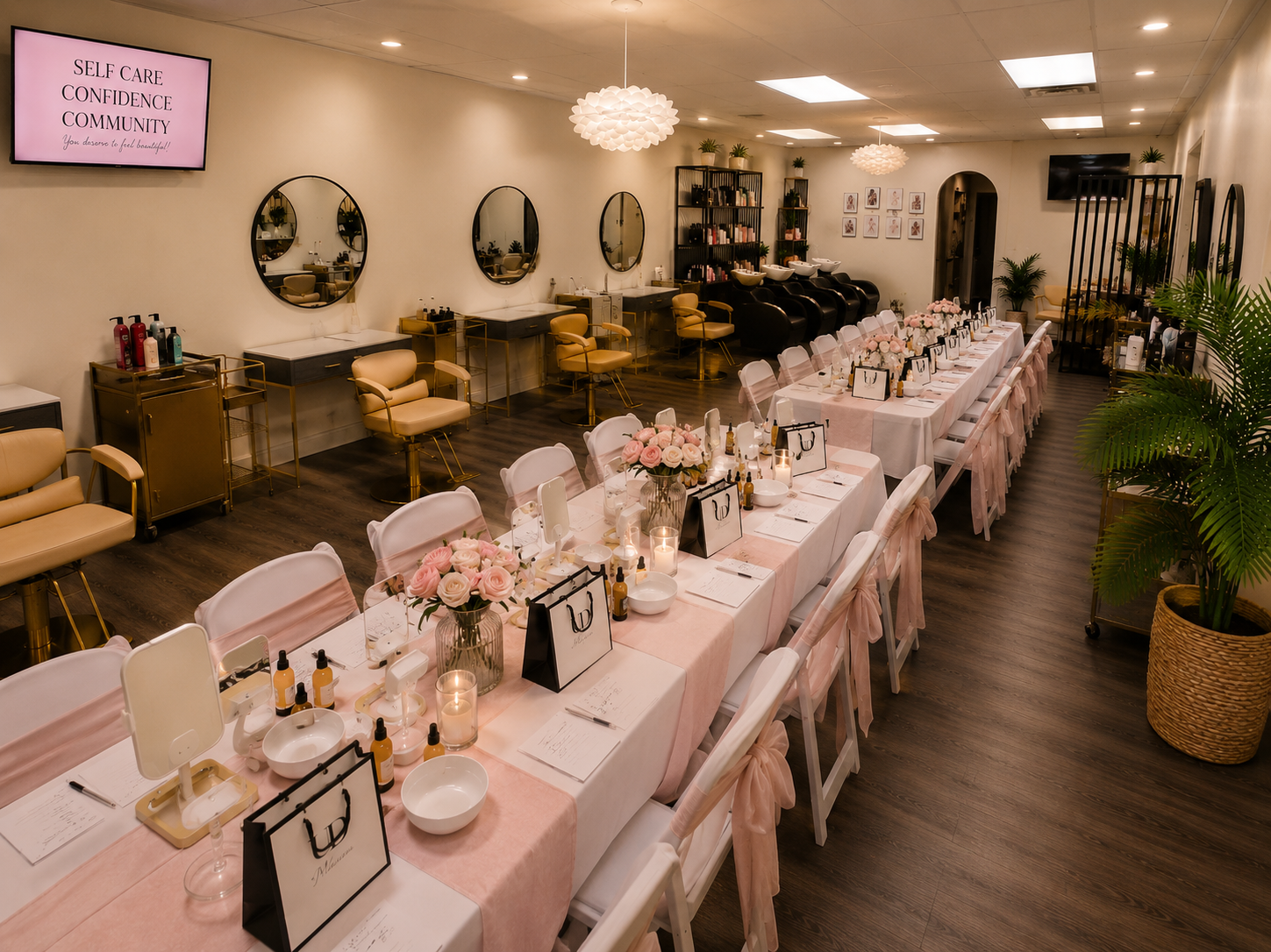 Salon event setup with long pink tables, roses, and candles