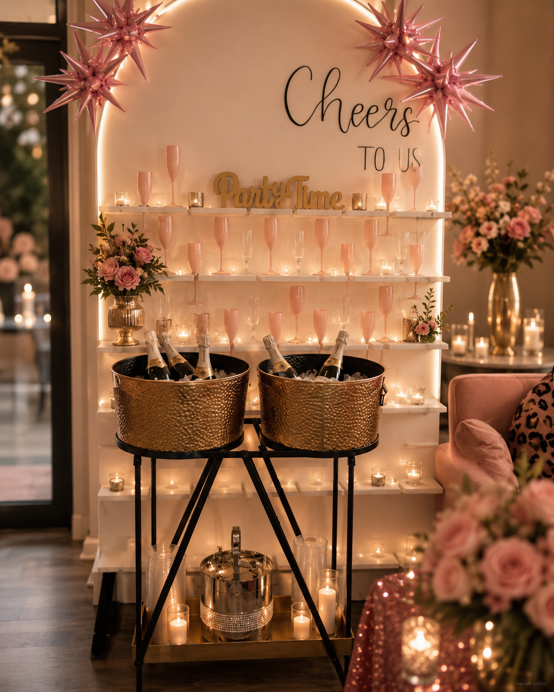Champagne wall with gold ice buckets, blush flutes, and pink star decor