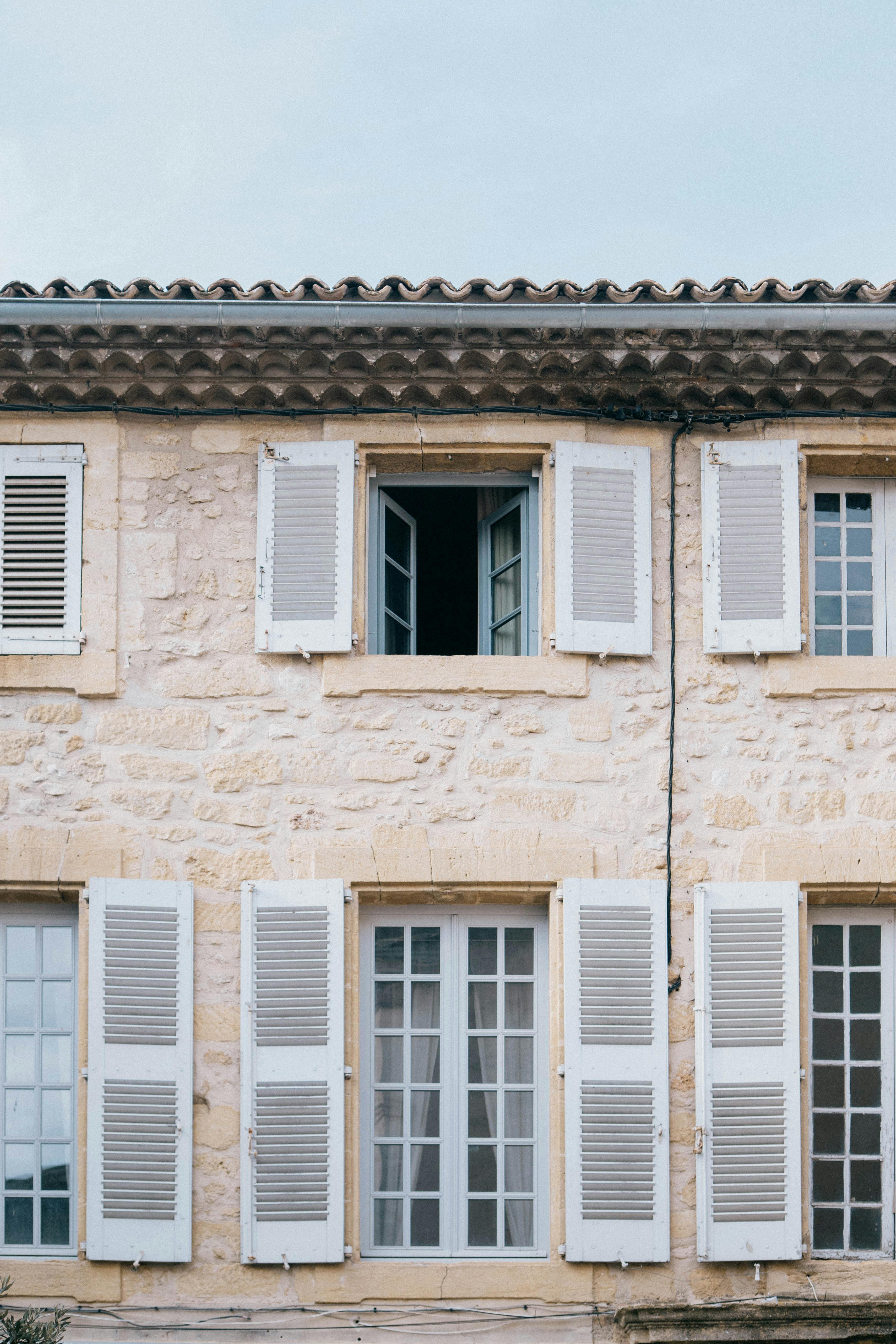Façade en pierre d'une maison valaisanne avec volets blancs typiques du Valais