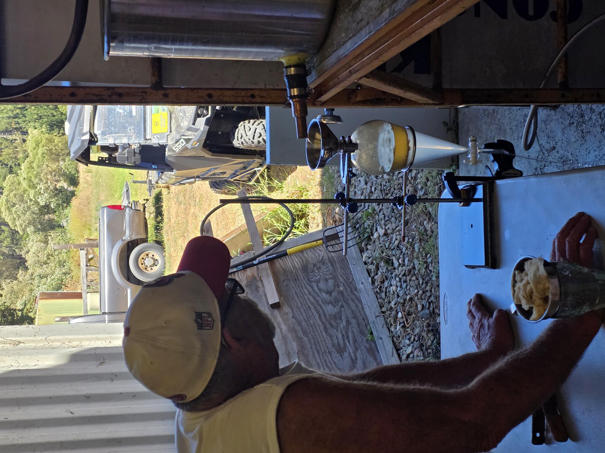 Two members of the Brenton Family Farms team working beside the distillation still