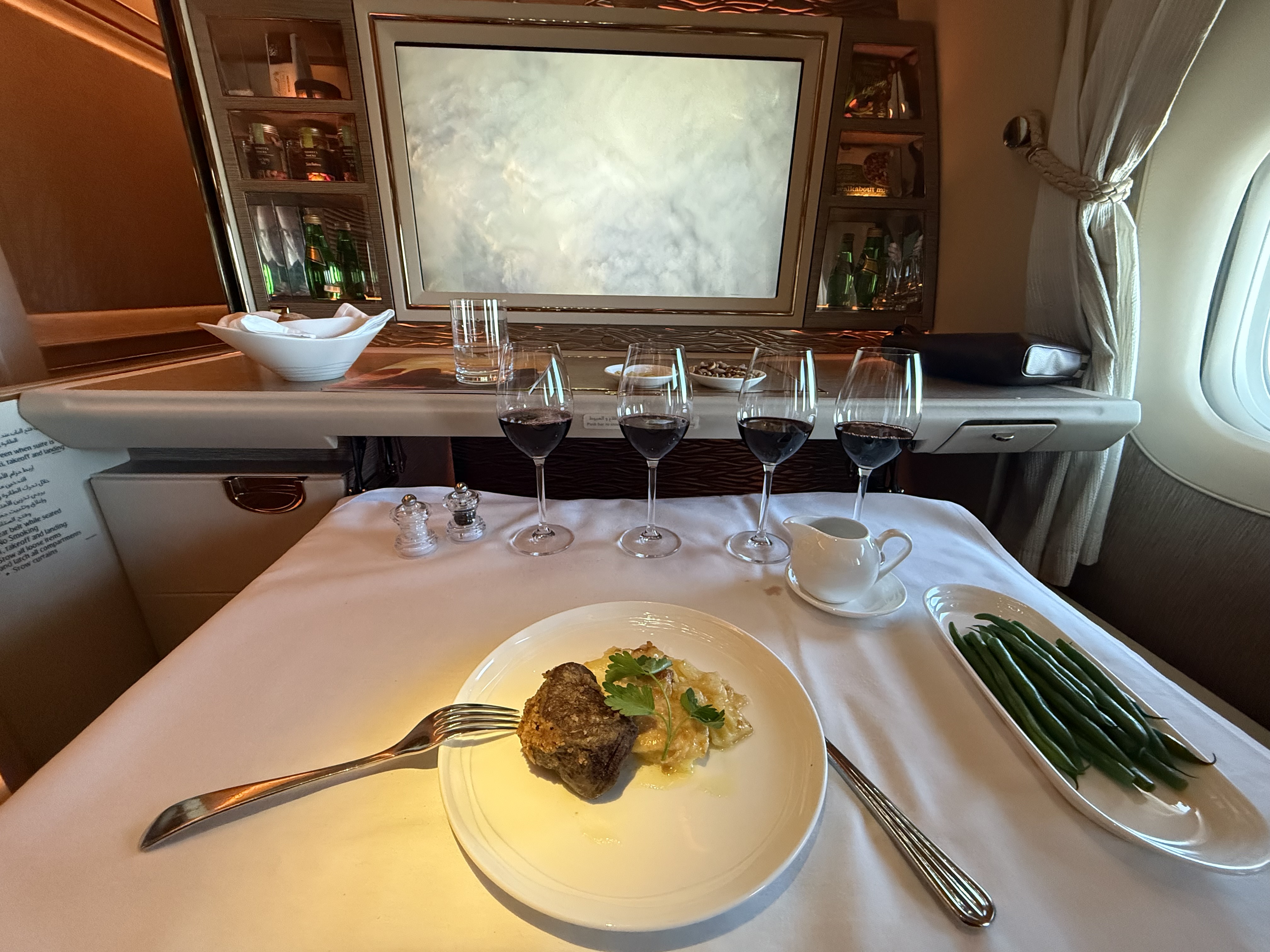 Emirates First Class dining experience with wine flight and steak dinner on white tablecloth