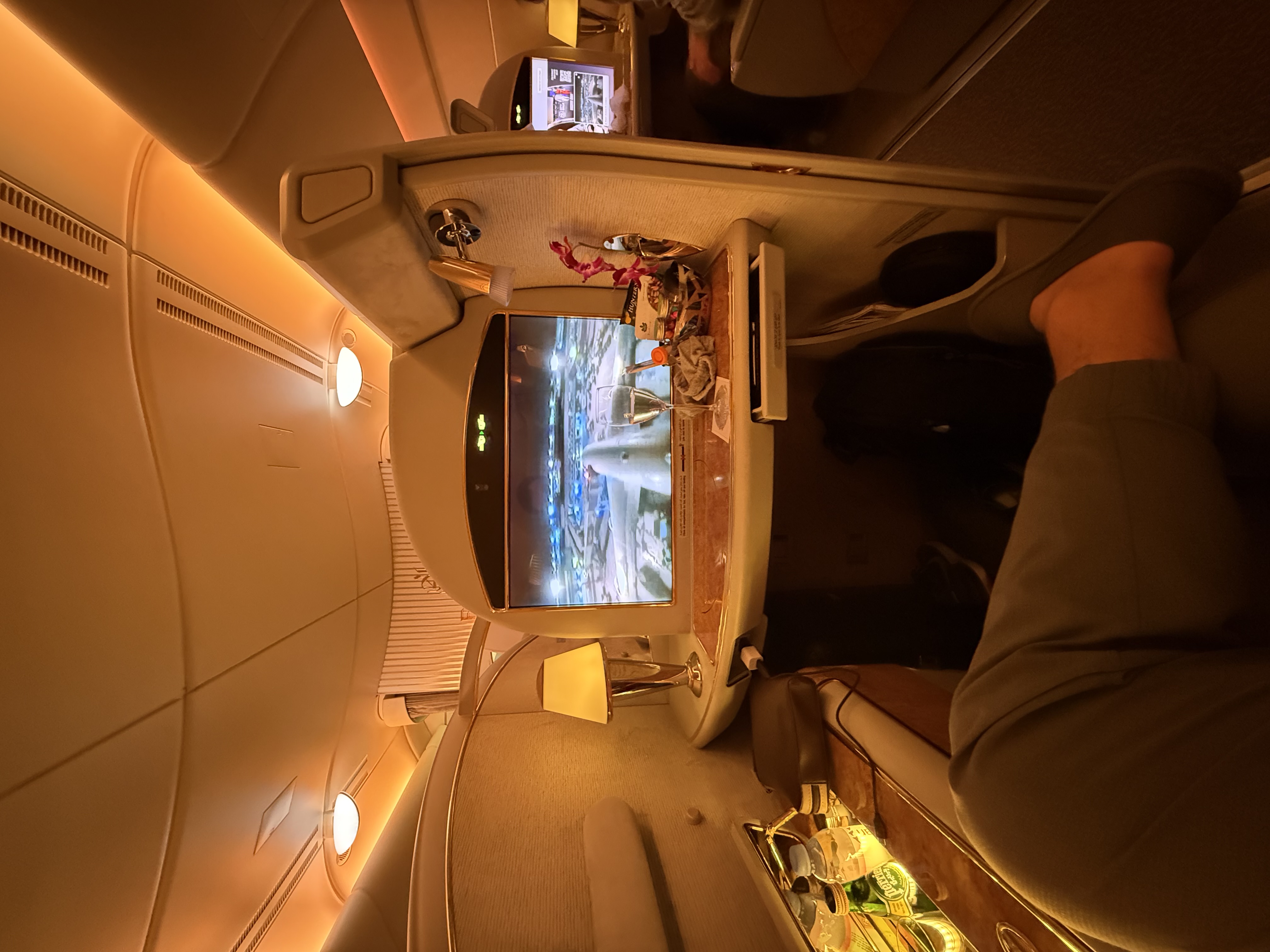 POV from Emirates First Class suite watching the tail camera with champagne on the side table