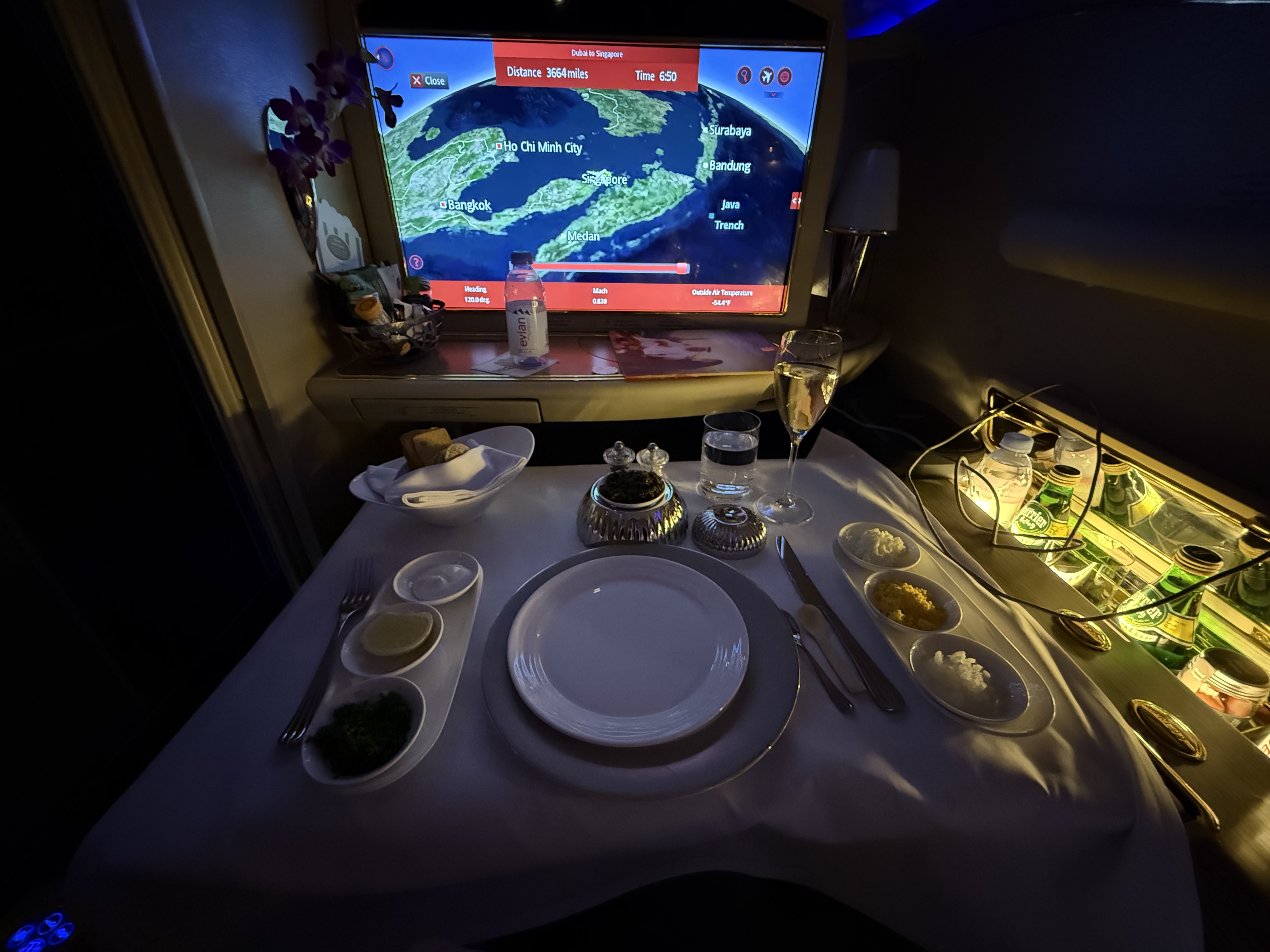 Emirates First Class night dining with caviar service and Dubai-to-Singapore flight map on screen