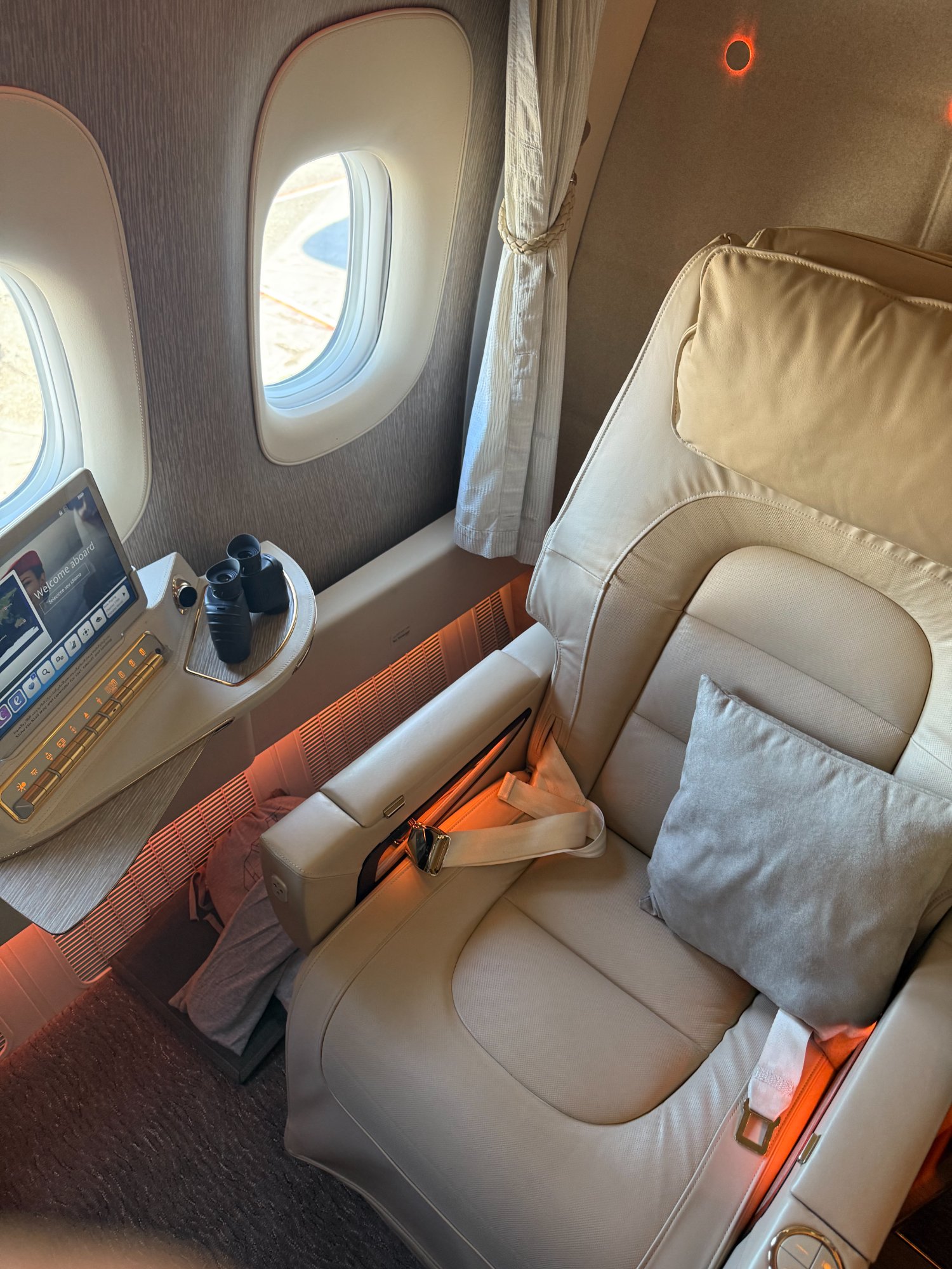 Emirates First Class private suite with ambient lighting and binoculars on the side table