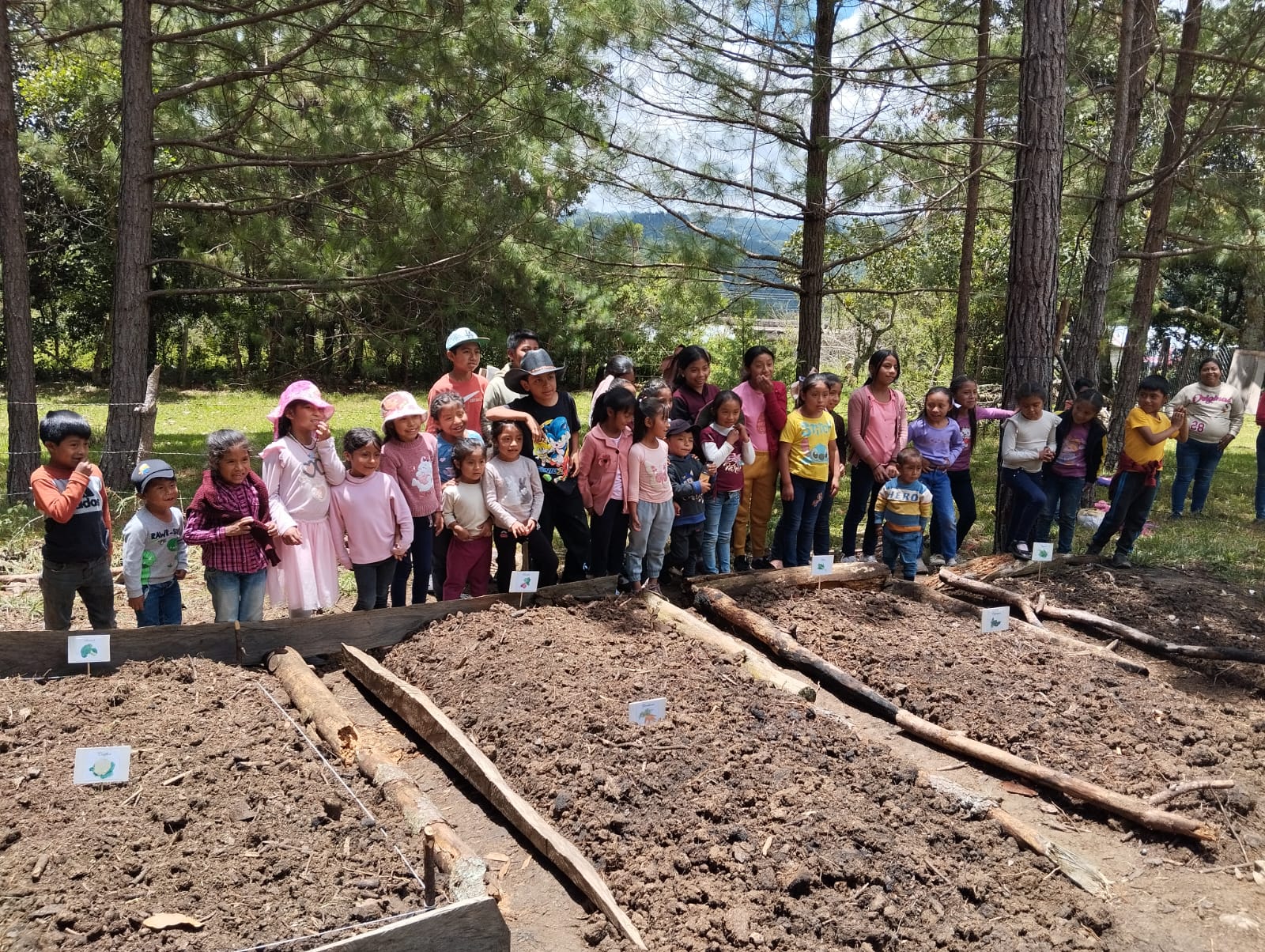 Children gathered around the community garden beds in Chiapas