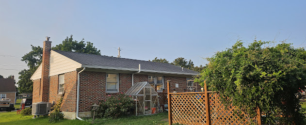 Completed back view of brick ranch — new architectural shingles, back porch, finished home exterior