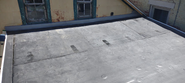 Old EPDM membrane on flat roof before replacement — weathered rubber membrane showing wear and deterioration
