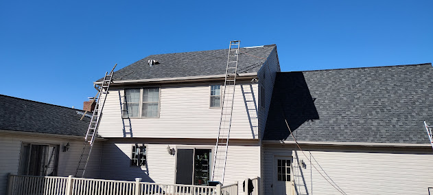 Different angle of farmhouse roof mid-install — new architectural shingles progressing across full pitch