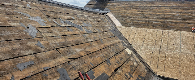 Tear-off complete — old plywood decking exposed and removed, new OSB sheathing partially installed over rafters