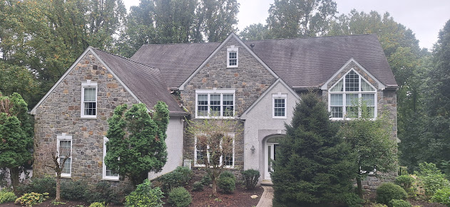 Aged weathered shingles on stone facade estate home — roof showing years of wear before replacement in Pennsylvania