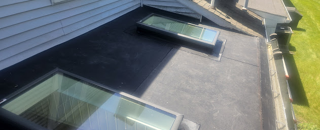 Finished EPDM flat roof with skylights installed — clean rubber membrane, sealed skylight flashing, professional finish