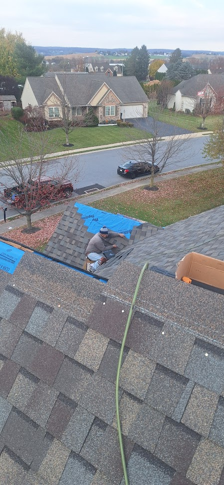 Roof Recovery installer working on shingles on stone accent colonial rooftop — neighborhood perspective in Pennsylvania