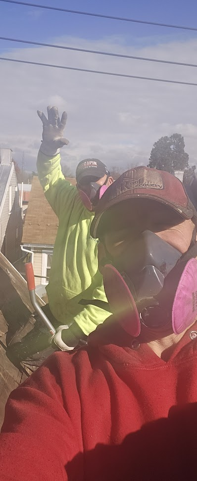 Roof Recovery crew wearing respirators during asbestos shingle removal — safety equipment on urban job site