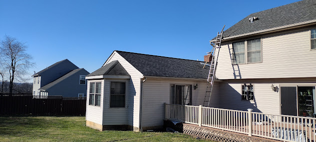 Farmhouse roof near completion — new architectural shingles nearly covering full pitch with clean ridge line