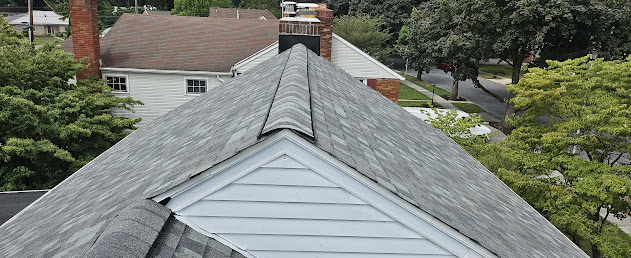 Finished architectural shingles on brick colonial — ridge cap and chimney flashing detail with architectural shingle texture