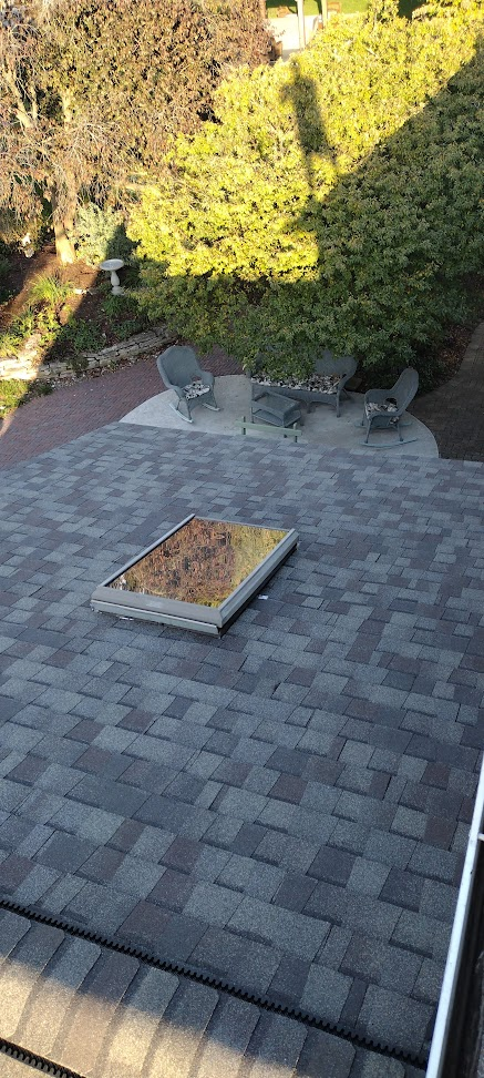 Skylight closeup with patio visible below — completed shingle roof replacement on upscale home