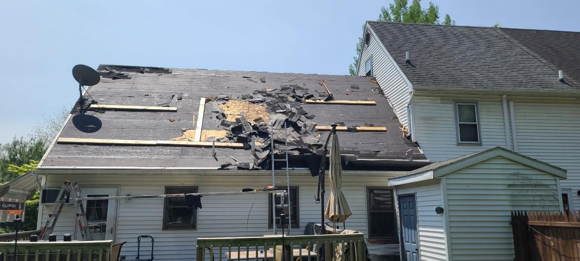 Roof tear-off in progress on Lebanon PA home — shingles stripped to plywood deck with ladder against house
