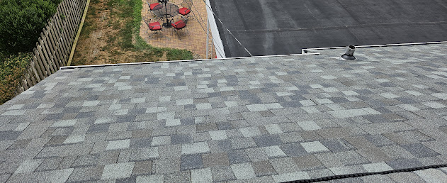 Finished shingles rooftop angle showing brick colonial home and patio below — full roof replacement visible