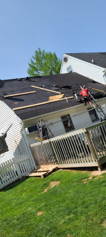 Crew member installing underlayment on Cape Cod roof — synthetic felt being rolled out over plywood deck