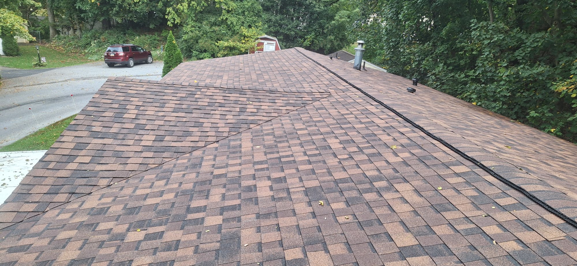 Completed large roof replacement Pennsylvania — new multi-tone brown architectural shingles with ridge vent, rooftop view