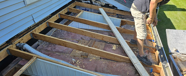 Flat roof rebuild in progress — exposed rafters and new insulation during EPDM deck restoration