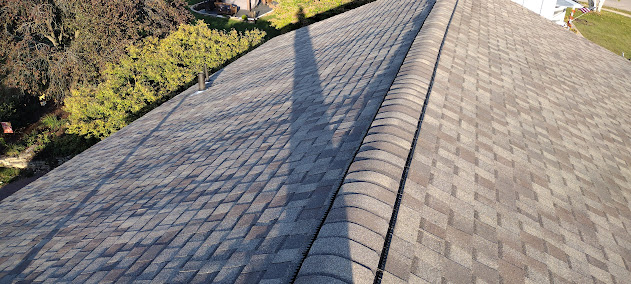 Ridge cap detail on completed architectural shingle roof replacement — clean ridge line on upscale home