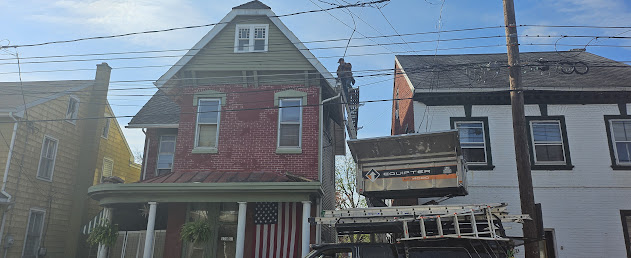 Crew on roof with Equipter raised and branded Roof Recovery truck visible on street — Lebanon PA