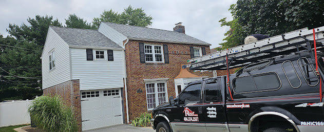 Completed brick colonial roof replacement — street view with branded Roof Recovery truck parked in front