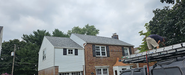 Roof Recovery crew member on ladder at brick colonial job site — work in progress with installer positioned