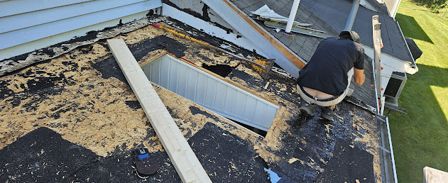 Flat roof tear-off in progress — old deteriorated EPDM membrane stripped, exposed roof decking visible